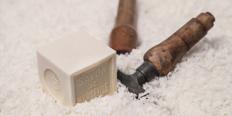 Cube de Savon de Marseille de 600g sur copeaux et entouré de tampons à savon